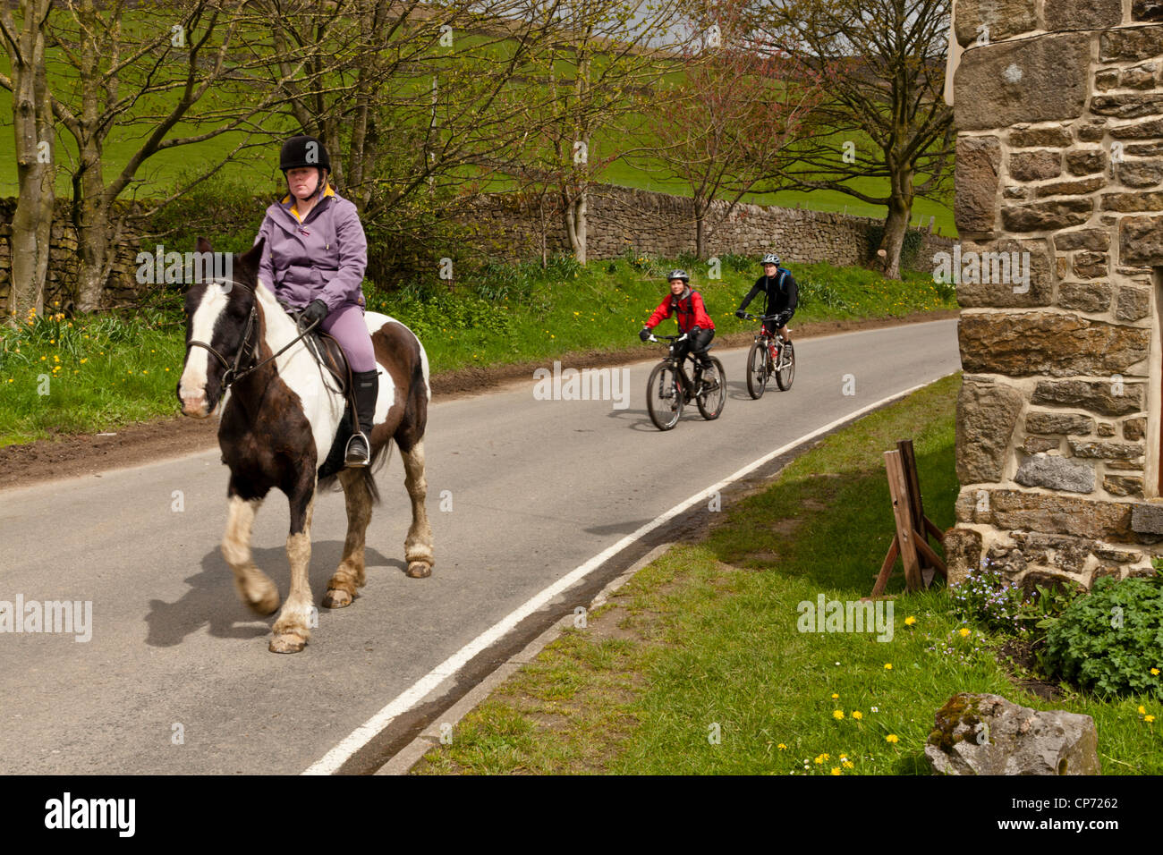 La equitación y el ciclismo en una carretera en el campo, Derbyshire Peak District, Inglaterra, Reino Unido. Foto de stock