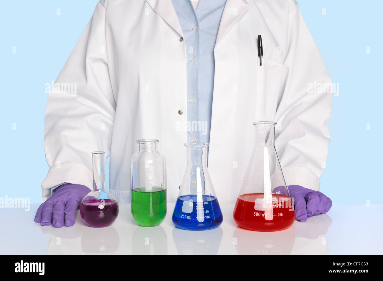 Foto de un profesor de química o científico de pie en un escritorio/contador con una fila de productos químicos Foto de stock