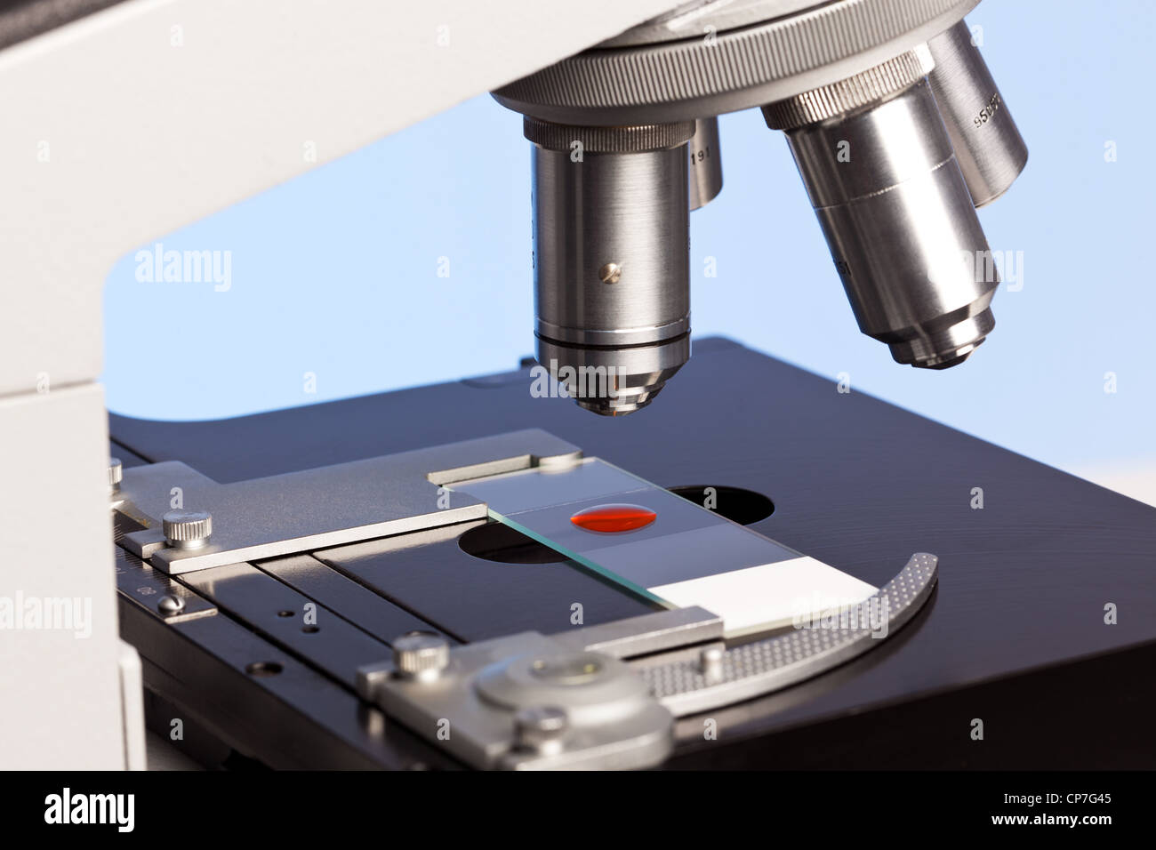 Foto de un microscopio de laboratorio con una muestra de sangre en un portaobjetos de vidrio. Foto de stock
