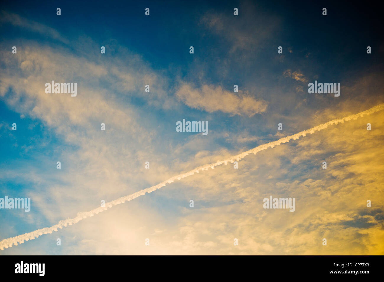 Las estelas de condensación de chorro de aerolíneas comerciales a través de un claro atardecer Atardecer cielo azul Foto de stock