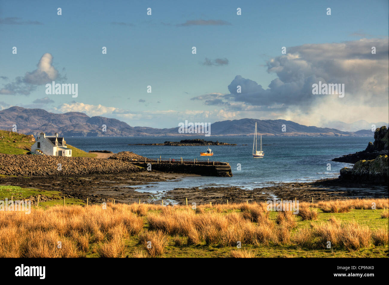 Un paisaje de puerto mor Isle of muck con barcos en la bahía y el continente en la parte trasera del terreno Foto de stock