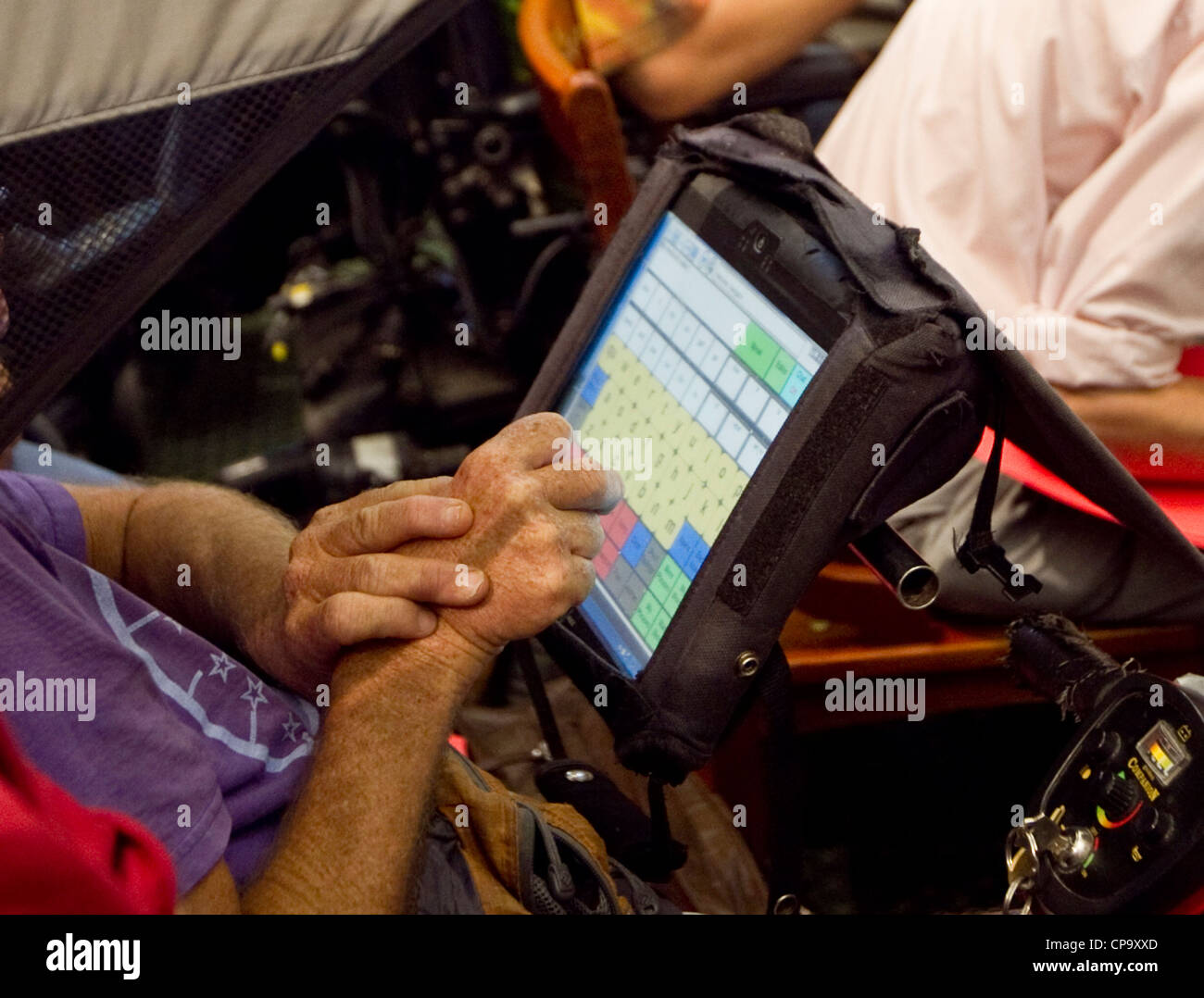 Discapacitados físicamente el hombre utiliza la pantalla táctil de ordenador acoplado a su silla de ruedas para comunicarse Foto de stock