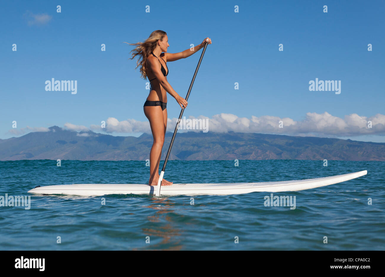 Colocar el Athletic mujer levántate remos en la Bahía de Napili, Maui, Hawai con Molokai en la distancia. Foto de stock