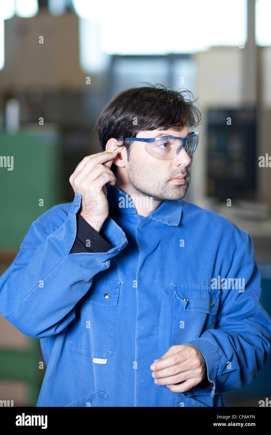 Obrero se preocupa por la protección de los oídos en un lugar de trabajo ruidoso Foto de stock