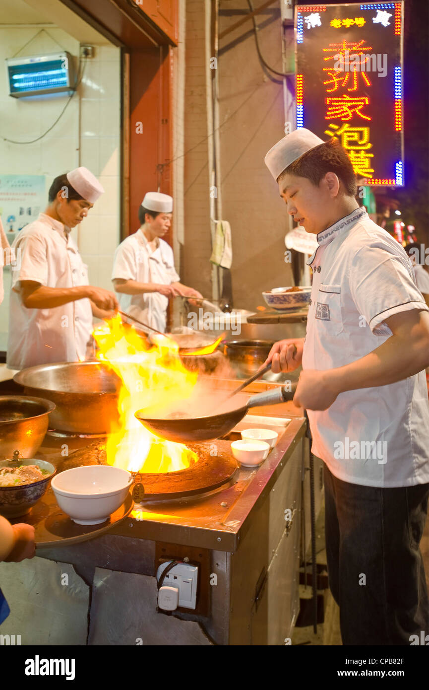 Los chefs chinos cocinar en una estufa de leña y gas tradicional wok en un  restaurante en la calle musulmana (Huimin Jie) en Xian Fotografía de stock  - Alamy