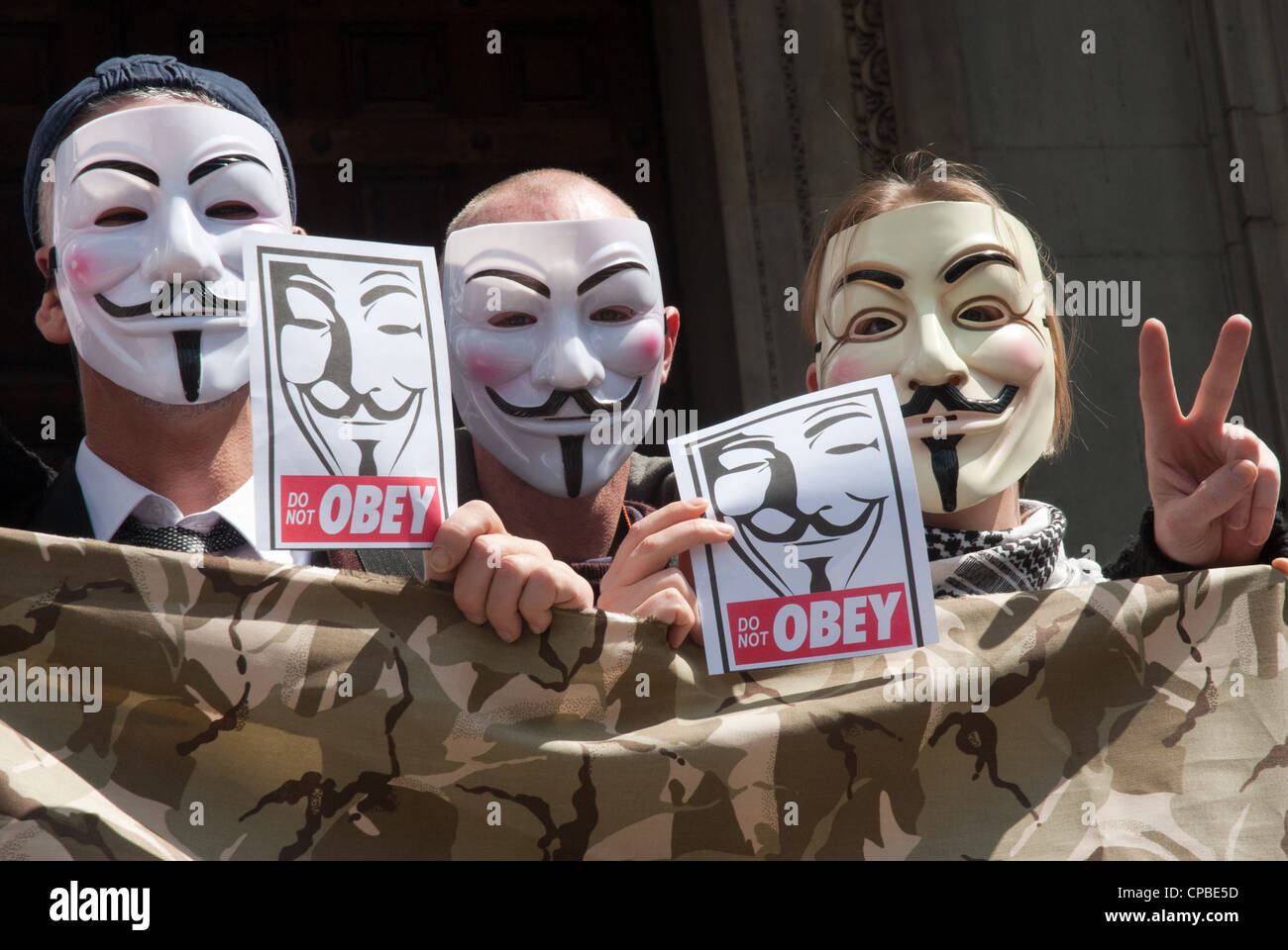 Ocupar, Londres, Reino Unido. Manifestación contra el capitalismo parte de un día de acción global. 3 manifestantes en Anonymous máscaras con carteles "no obedecer' Foto de stock