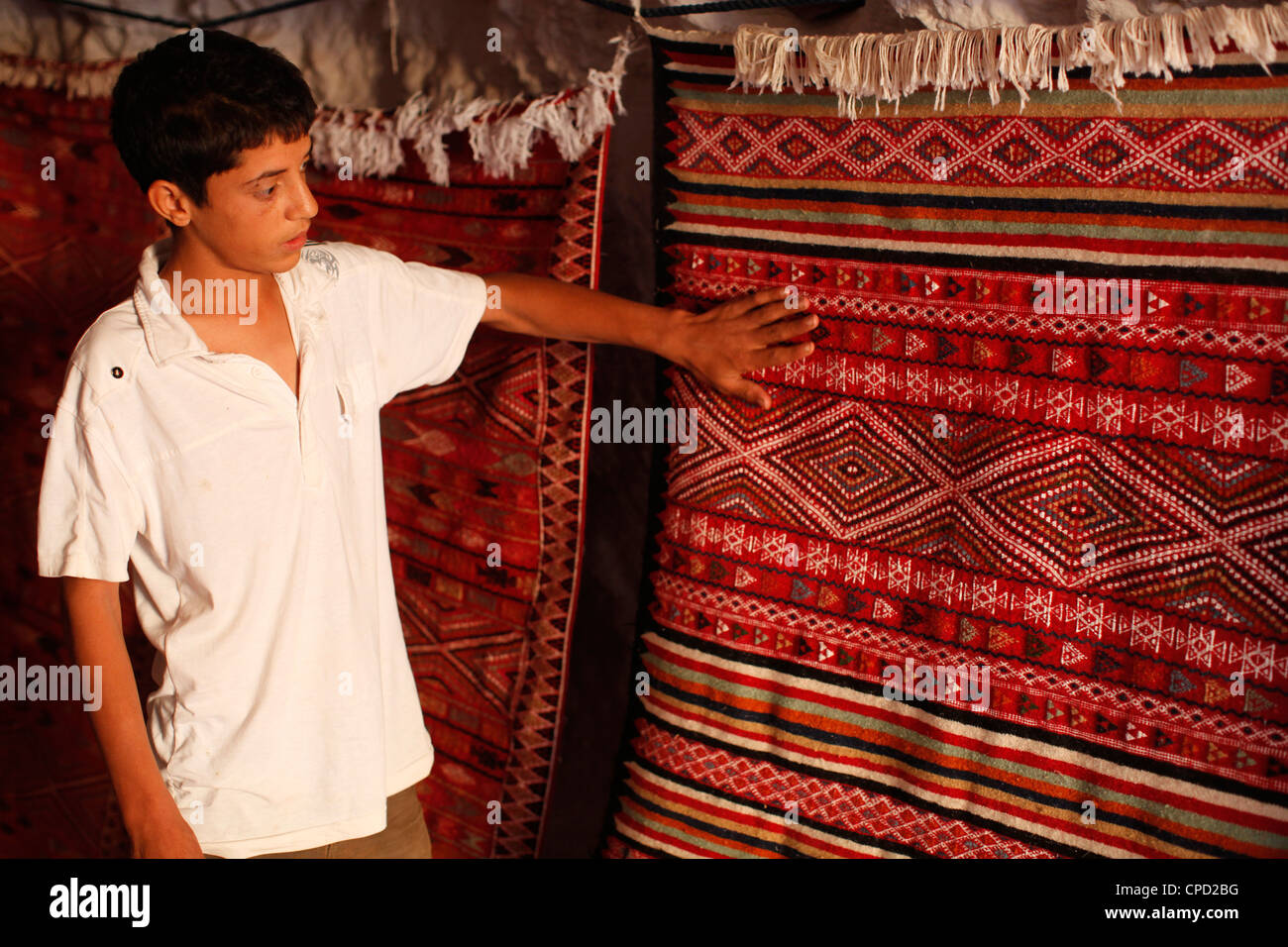 Boy mostrando una alfombra en una tienda de alfombras, Toujane, Túnez, África del Norte, África Foto de stock