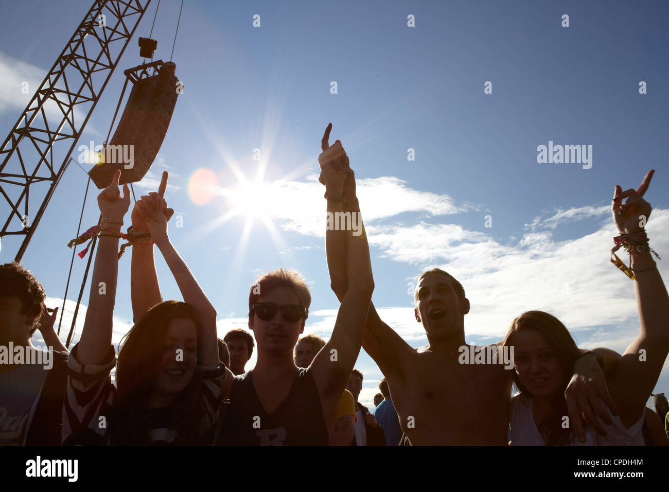 Jóvenes bailando y vitoreando al sol en una fiesta de música Foto de stock