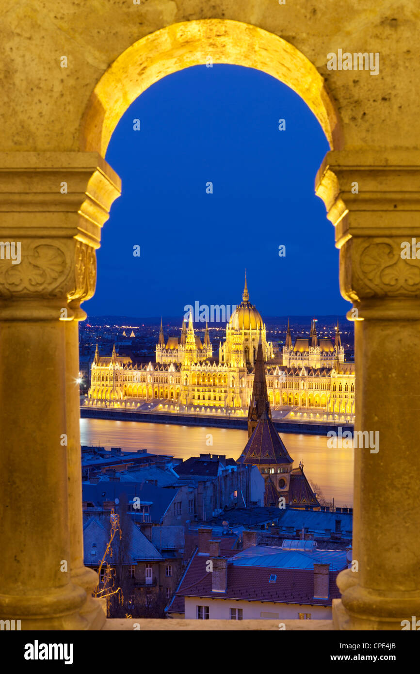 El Parlamento (Orszaghaz) mediante arcos de el bastión de los pescadores (Halaszbastya) al atardecer, Budapest, Hungría, Europa Foto de stock