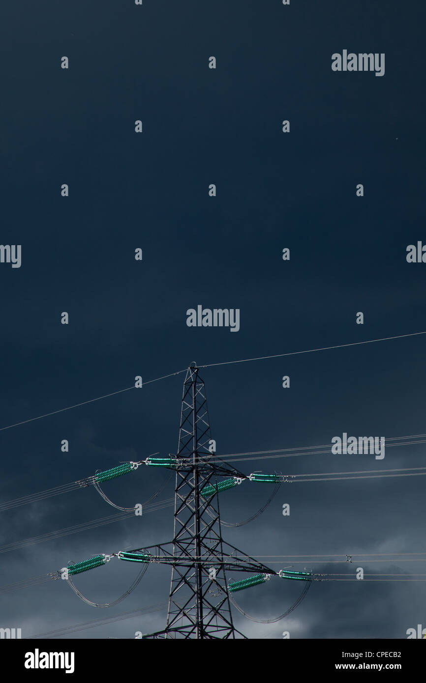 Poste eléctrico y cables de alimentación contra el oscuro cielo tormentoso,Inglaterra Foto de stock