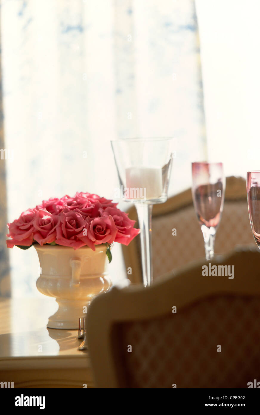 Rosas rosas en un jarrón sobre la mesa de comedor Foto de stock