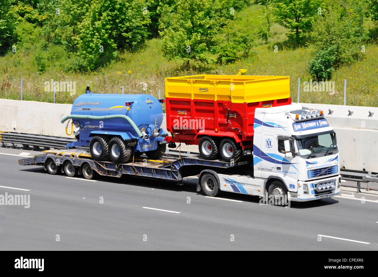 Cargador baja y nuevos equipos agrícolas Agrimac detrás de un camión Volvo Foto de stock
