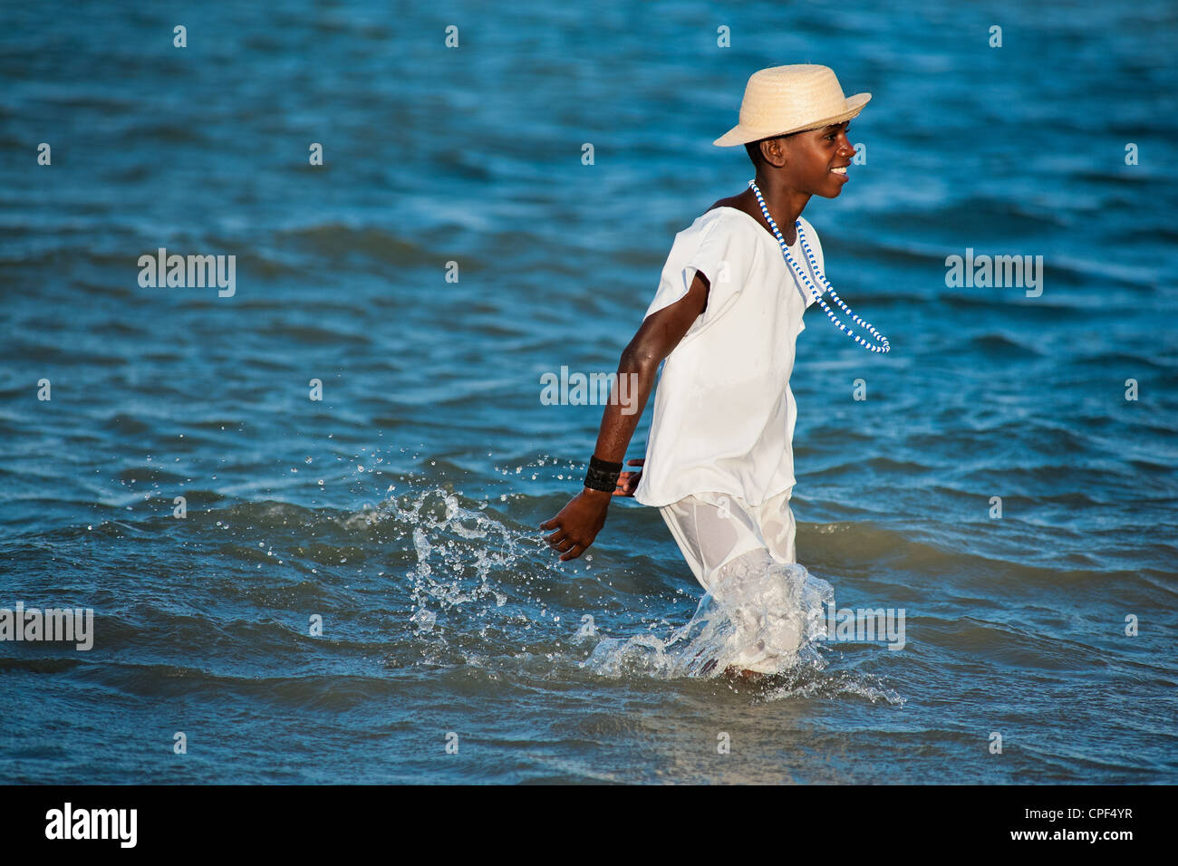 Un joven devoto de Candomblé vadeas en el mar durante el ritual de la procesión en honor a Yemanjá en Amoreiras, Bahia, Brasil. Foto de stock