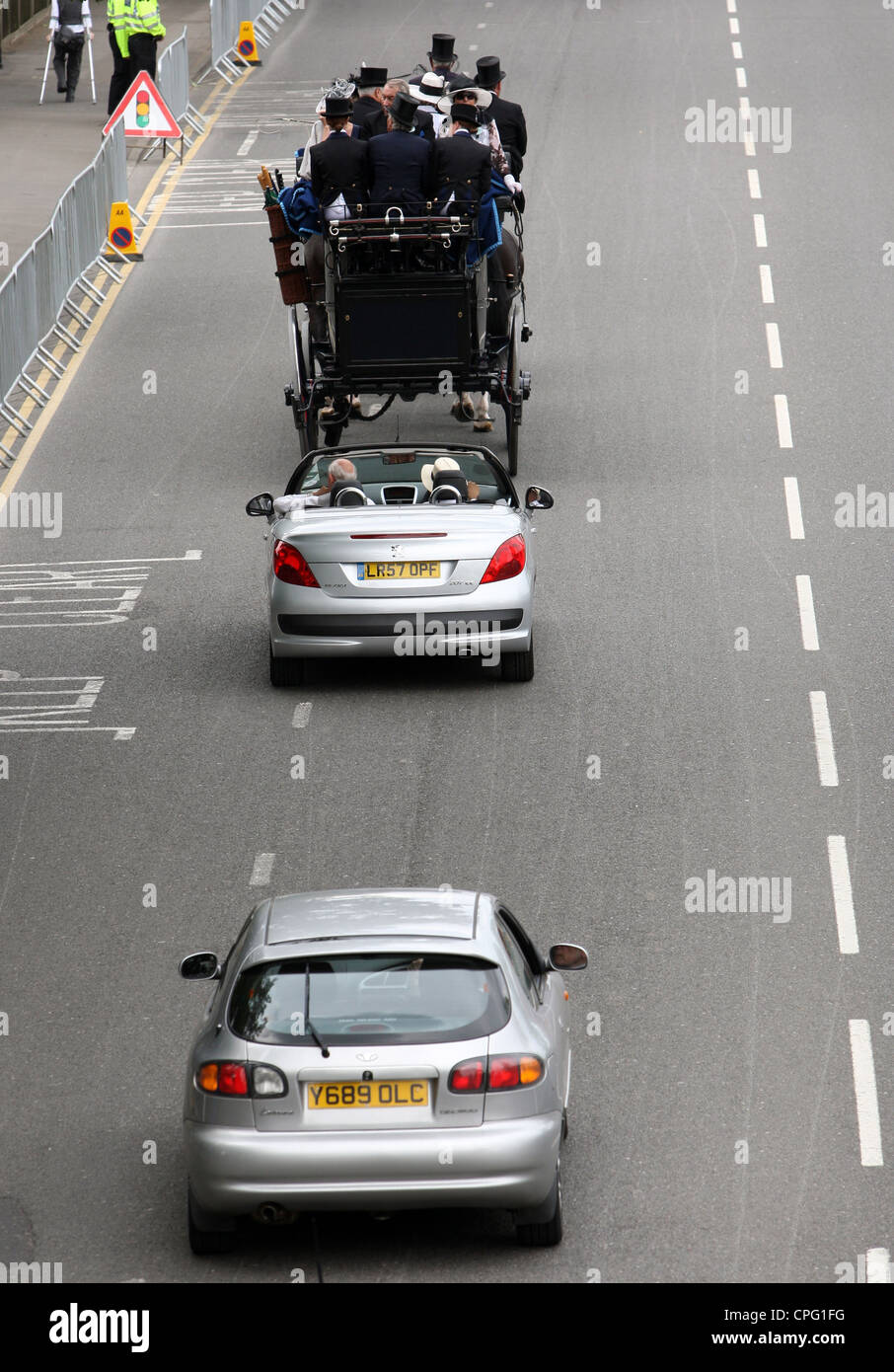 Automóviles circulando lentamente detrás de una calesa, Ascot, Reino Unido Foto de stock