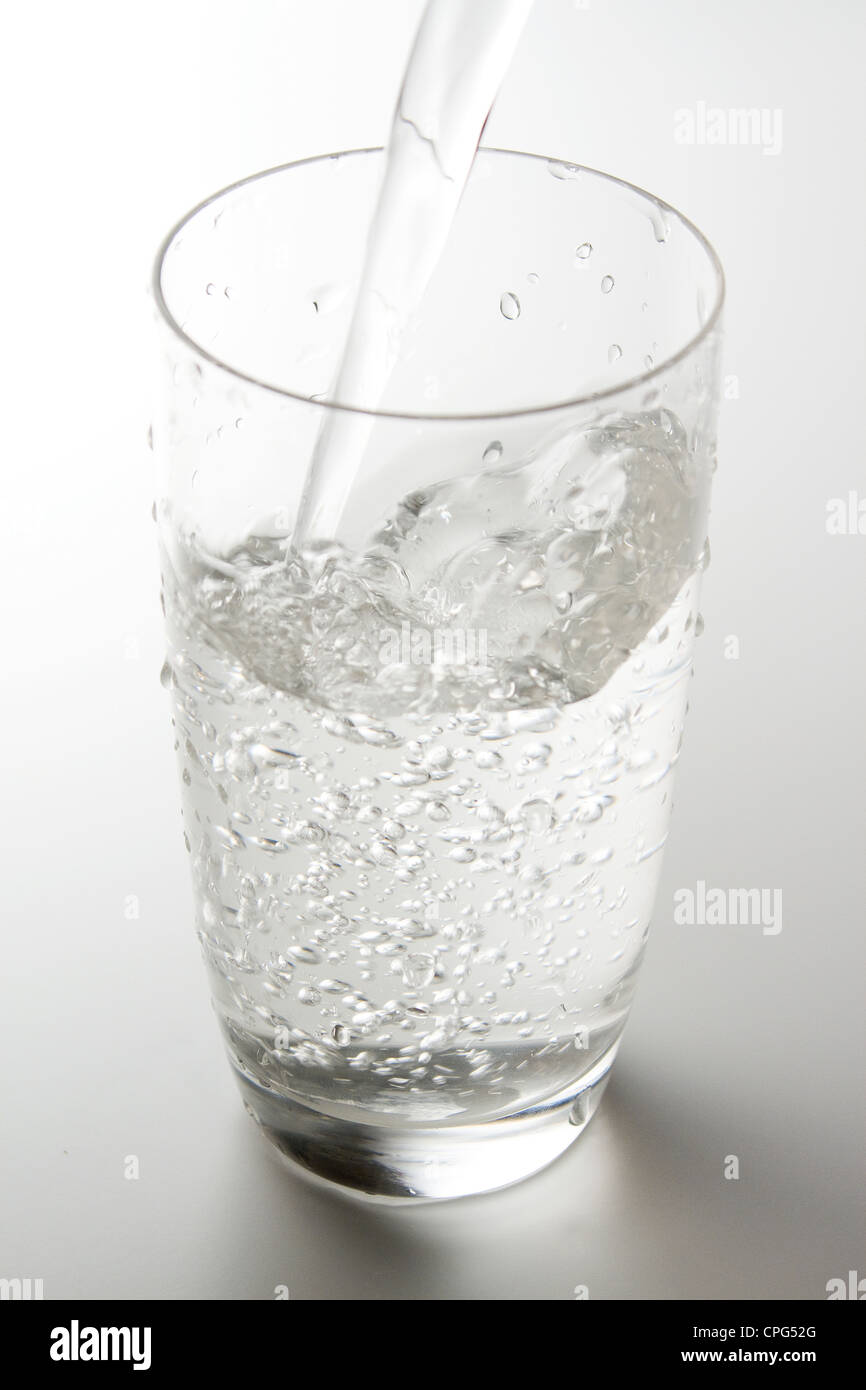 Verter agua en cristal con fondo liso Foto de stock