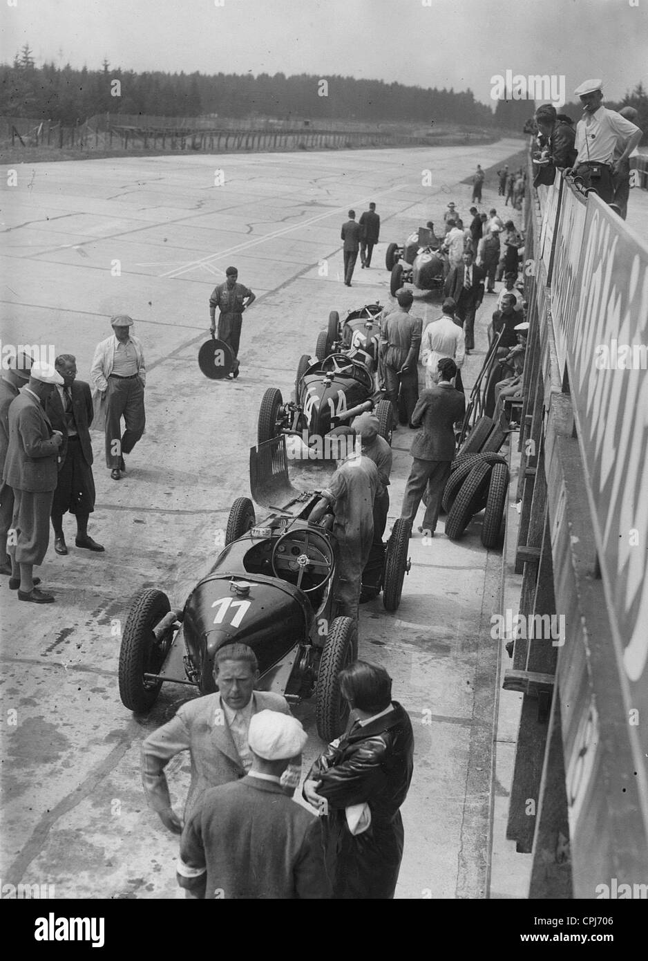 Mecánico de automóviles con coches de carreras y piezas de repuesto durante una sesión de entrenamiento en el Nuerburgring, 1935 Foto de stock