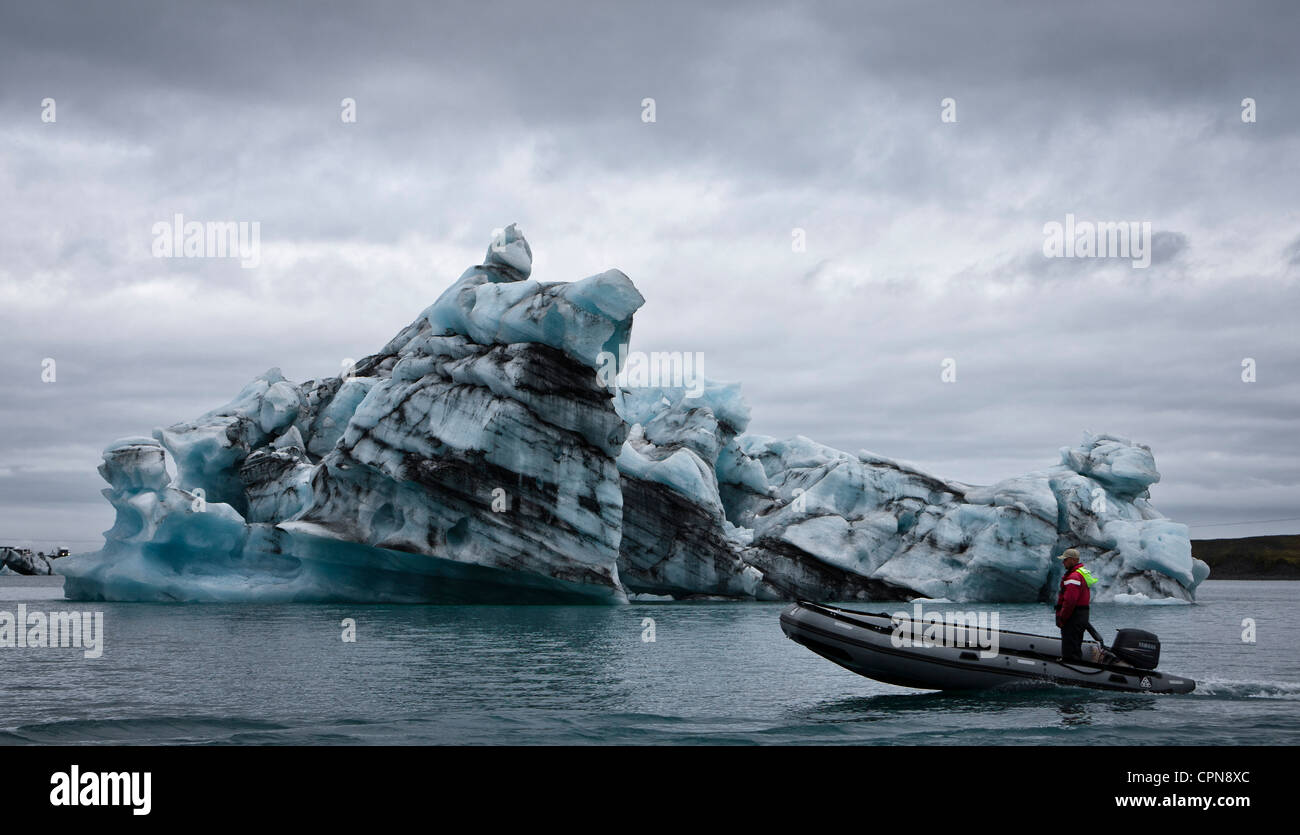 Barco de motor mueve más allá de iceberg en la Laguna glaciar Jokulsarlon, Islandia Foto de stock