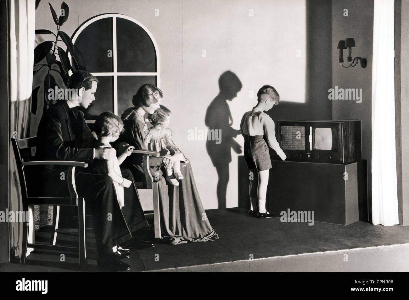 Broadcast,televisión,espectadores ficticios frente al televisor,fotografía  promocional para el E1,se presentó en el programa de radio 1939,contenía  como primer televisor en todo el mundo un tubo de imagen cuadrado,el E1 fue  construido en