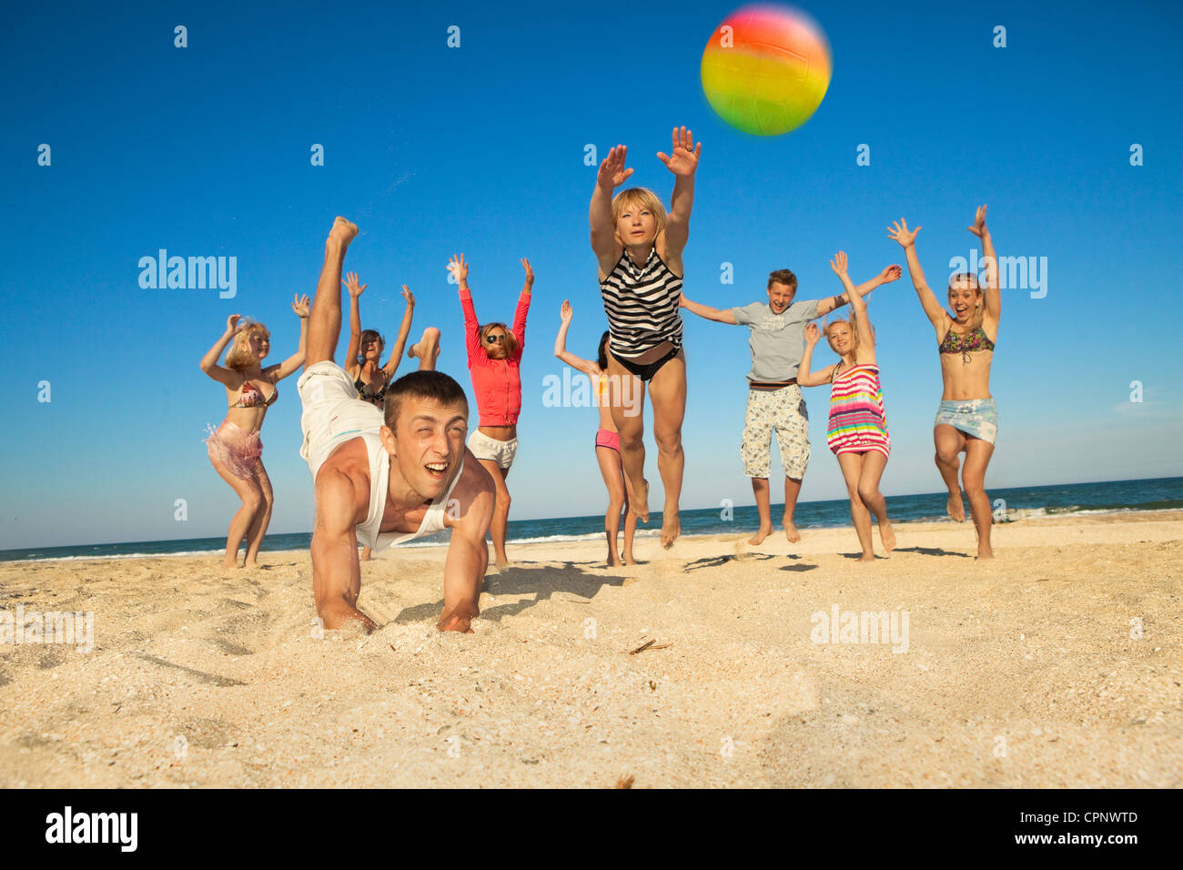 Grupo de jóvenes alegres juega al voleibol en la playa Foto de stock