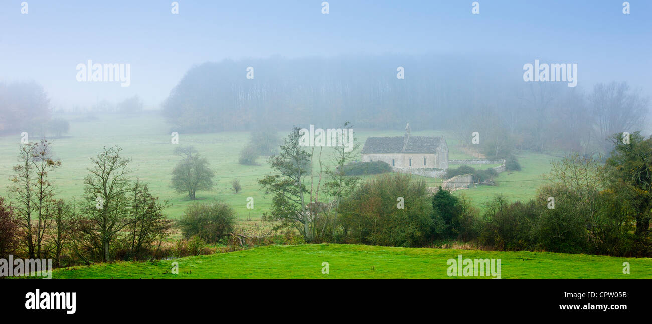 Misty escena y la iglesia de St Oswald, una capilla remota en un campo, en Widford cerca de Burford en Cotswolds, Oxfordshire, REINO UNIDO Foto de stock