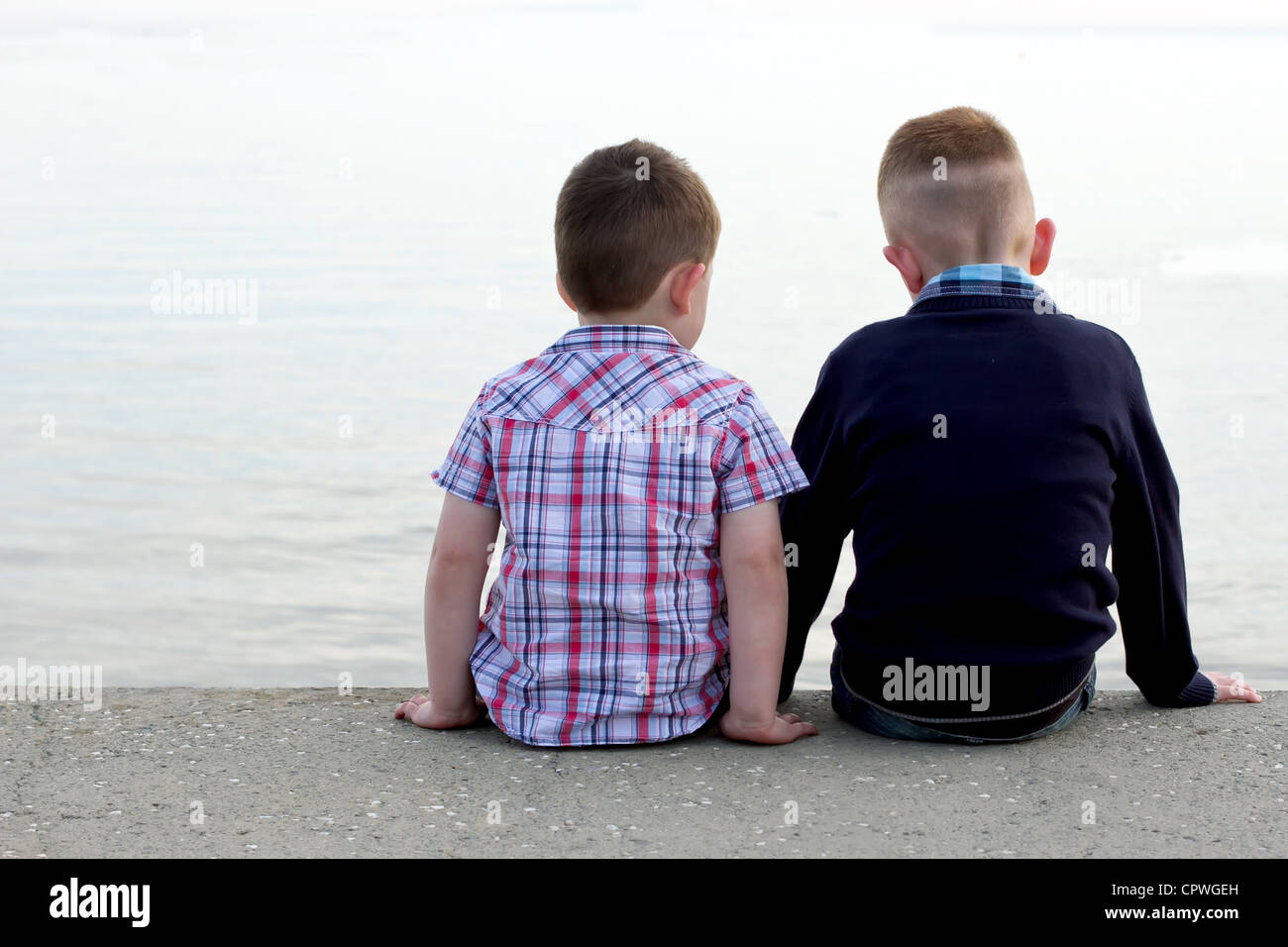 Dos hermanos sentados en una playa de Muro Foto de stock