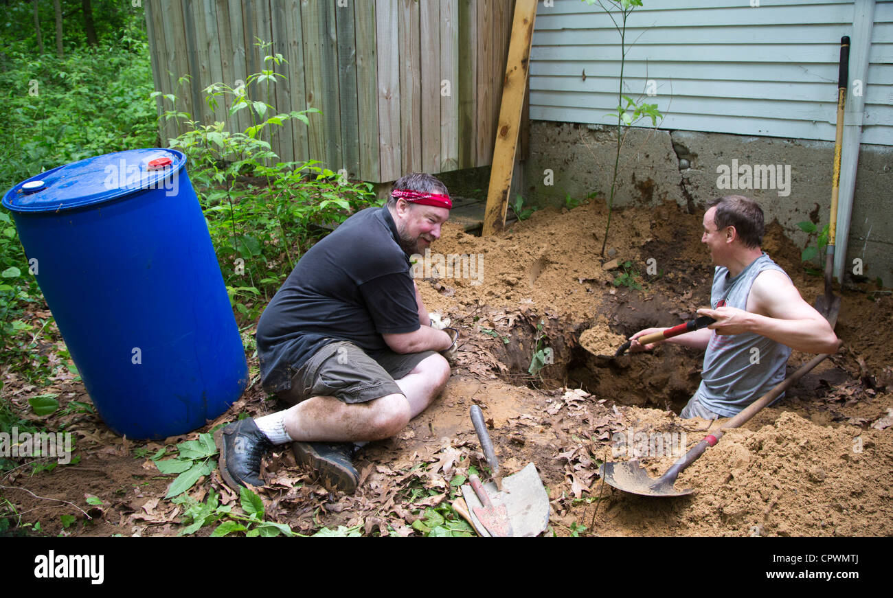 Los hombres cavar un agujero para instalar un pozo seco en una cabaña de verano que más carece de fontanería. Foto de stock