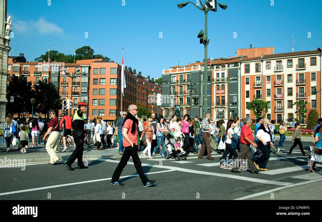 Los peatones en Bilbao movido por un policía de tránsito (boina roja, centro izquierda) en un cruce en Campo Valentin Foto de stock