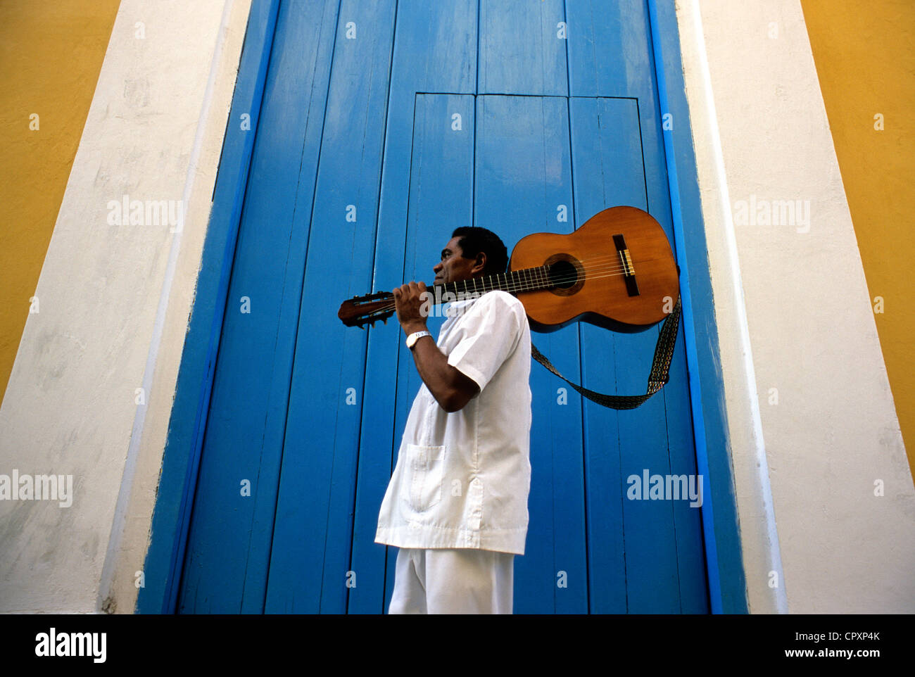 Cuba, La Habana, La Habana Vieja Distrito listados como Patrimonio Mundial por la UNESCO, músico llevando una guitarra en frente de la fachada de color Foto de stock
