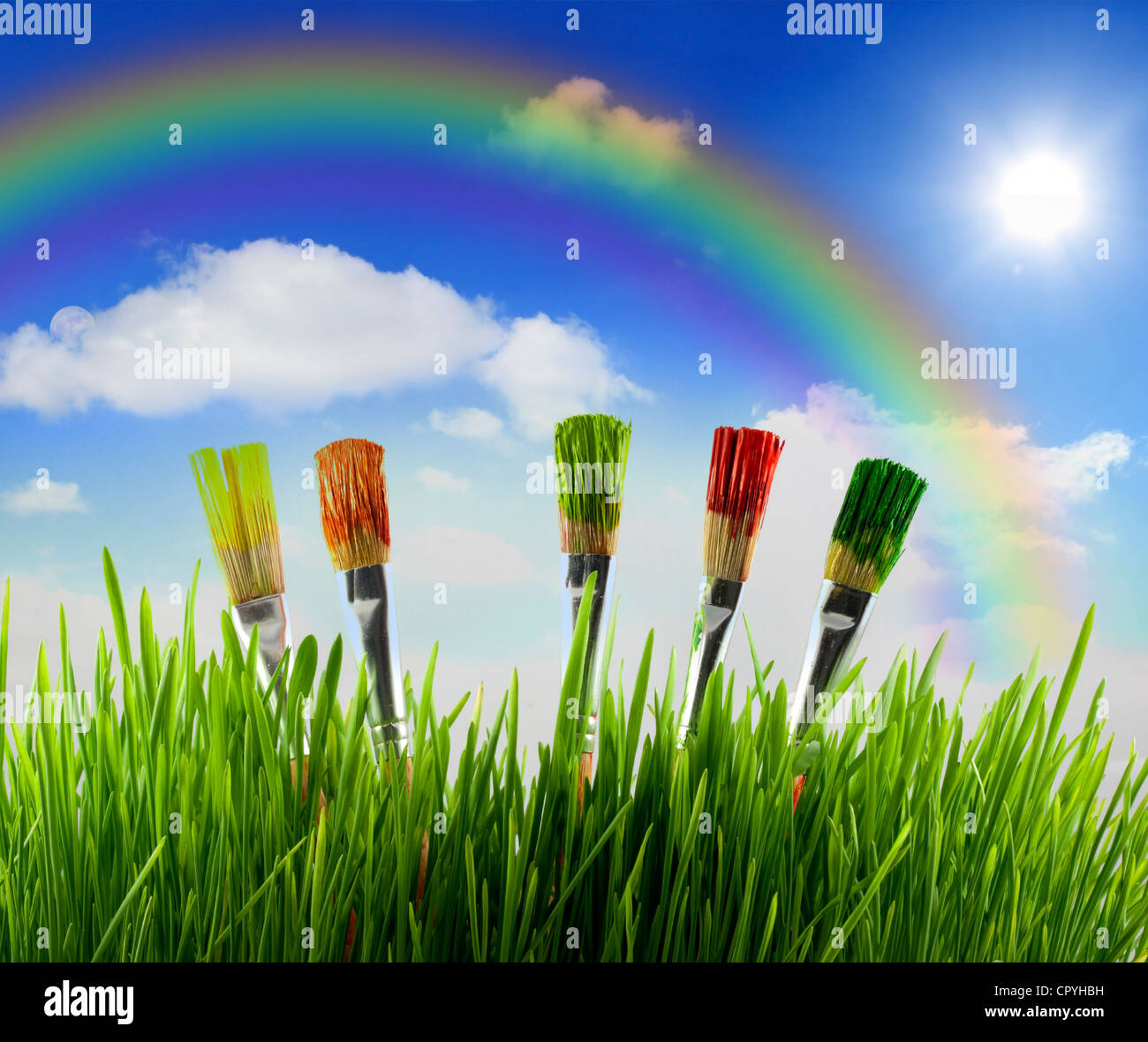 Los colores de la naturaleza con el pasto verde y brochas de pintura contra rainbow Foto de stock