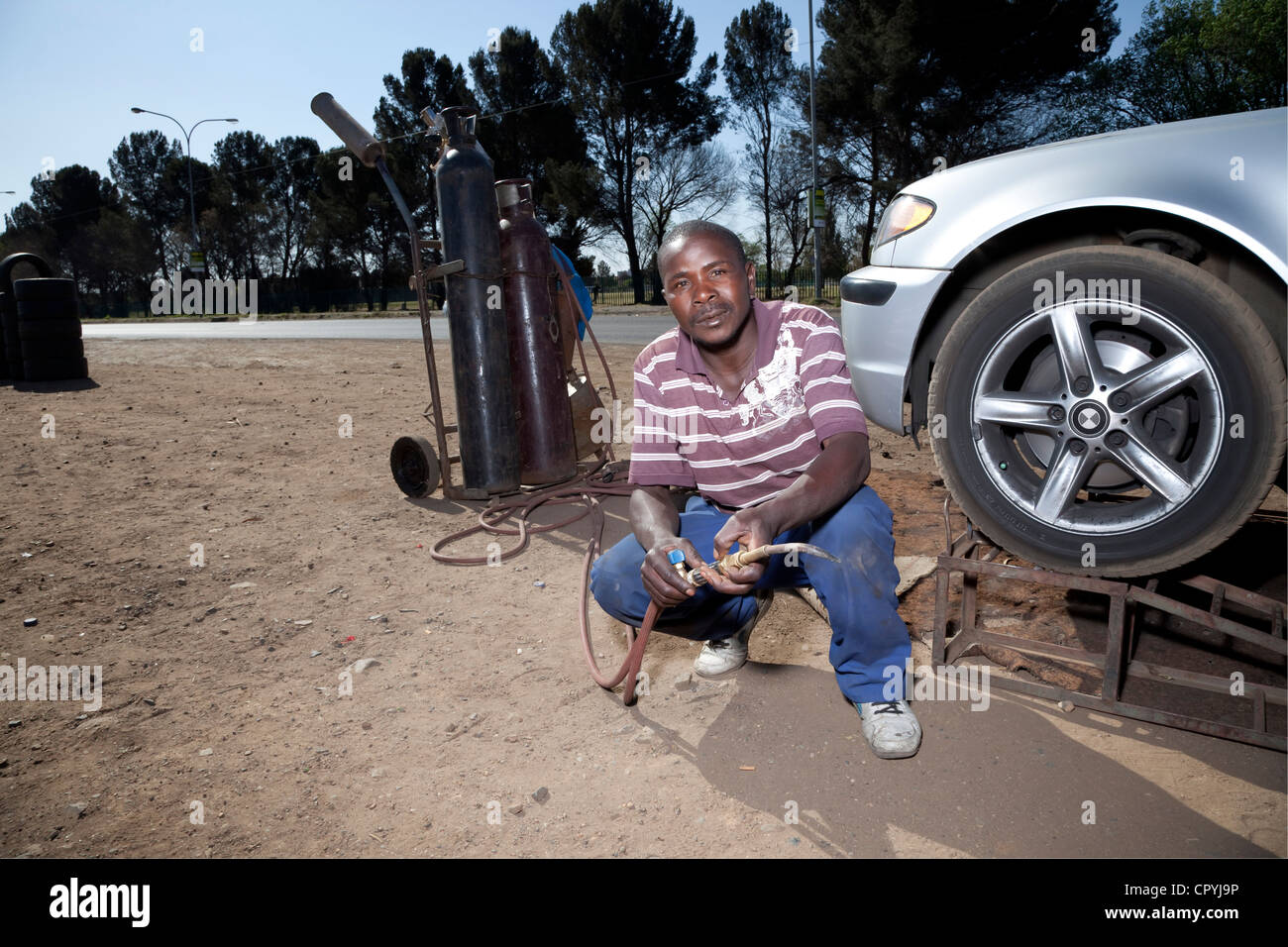 Joven negro se encuentra en una carretera con un kit de soldadura Foto de stock