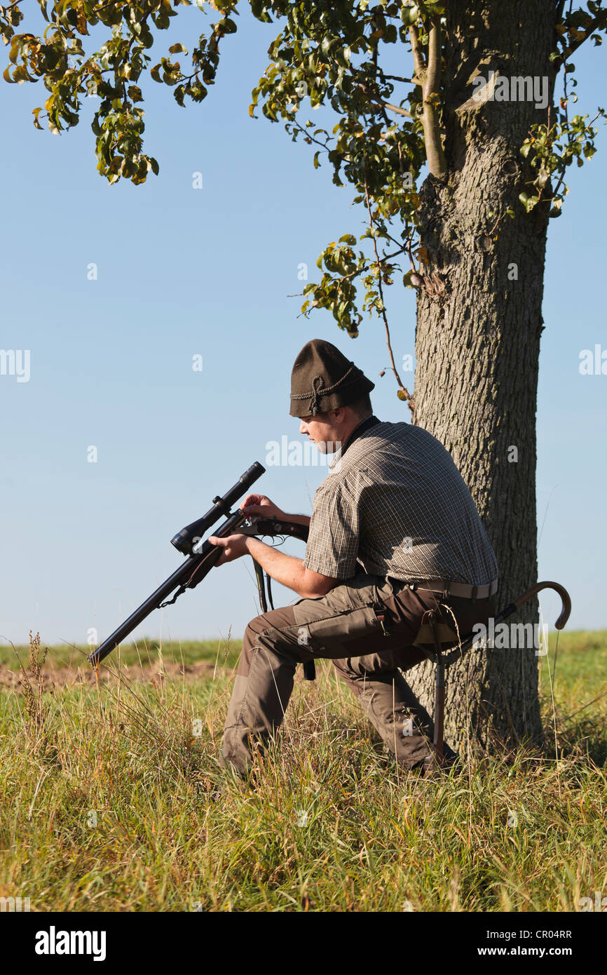 Hunter en un impulsado hunt, recargando su rifle Foto de stock