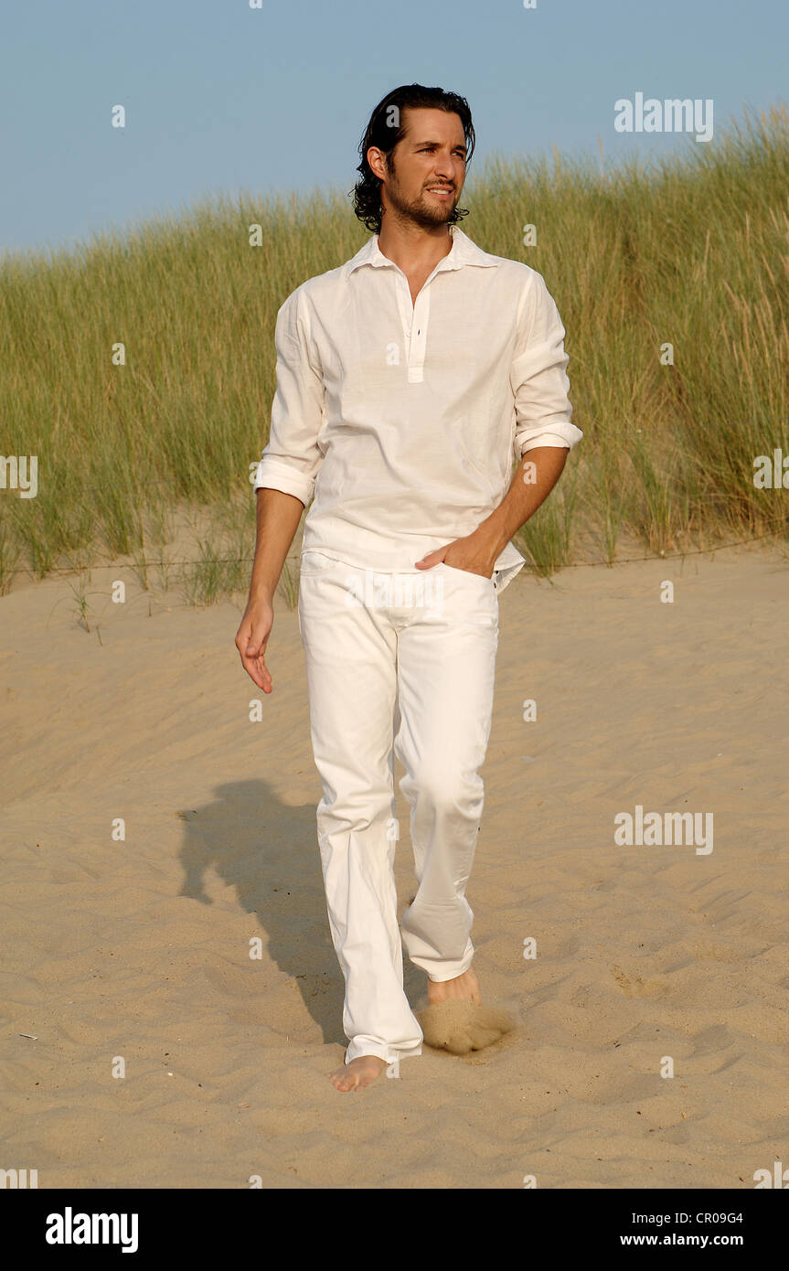 Hombre vestidos de blanco caminando por las dunas de la playa Fotografía de  stock - Alamy