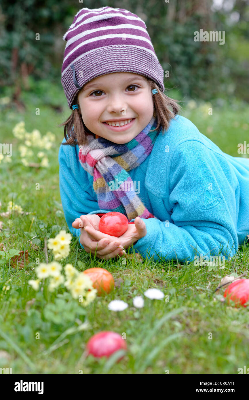 Chica con huevos de pascua en una pradera de primavera Foto de stock