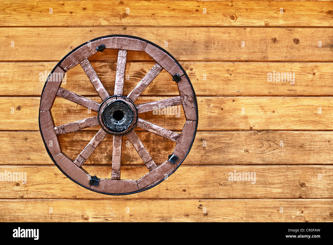 Un viejo Wagon Wheel decorado con una pared de madera Foto de stock