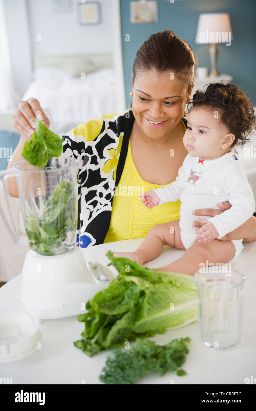 Mestizos madre sosteniendo el bebé y el uso de la batidora Fotografía de  stock - Alamy