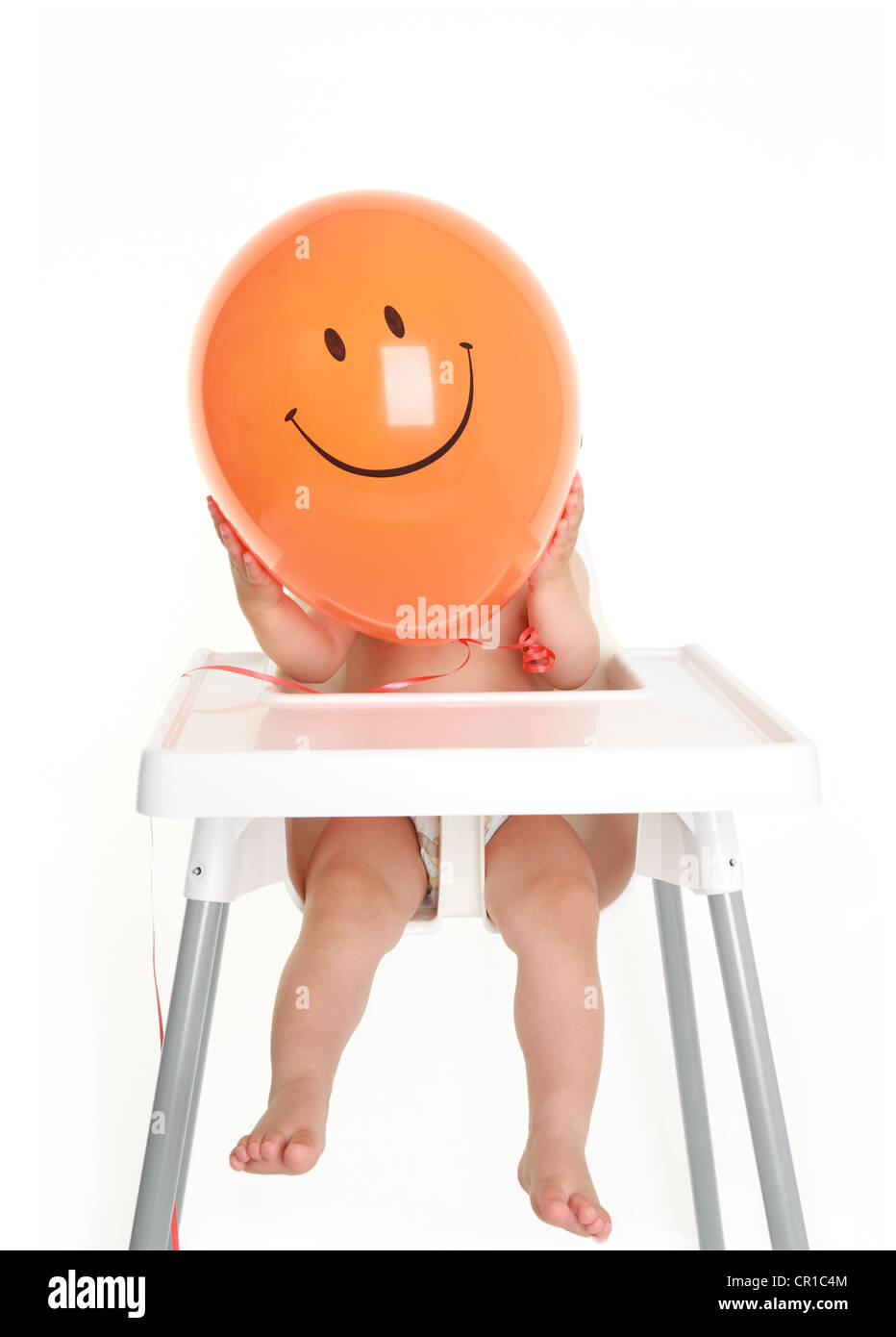 Bebé escondiéndose detrás de la cara feliz globo Foto de stock