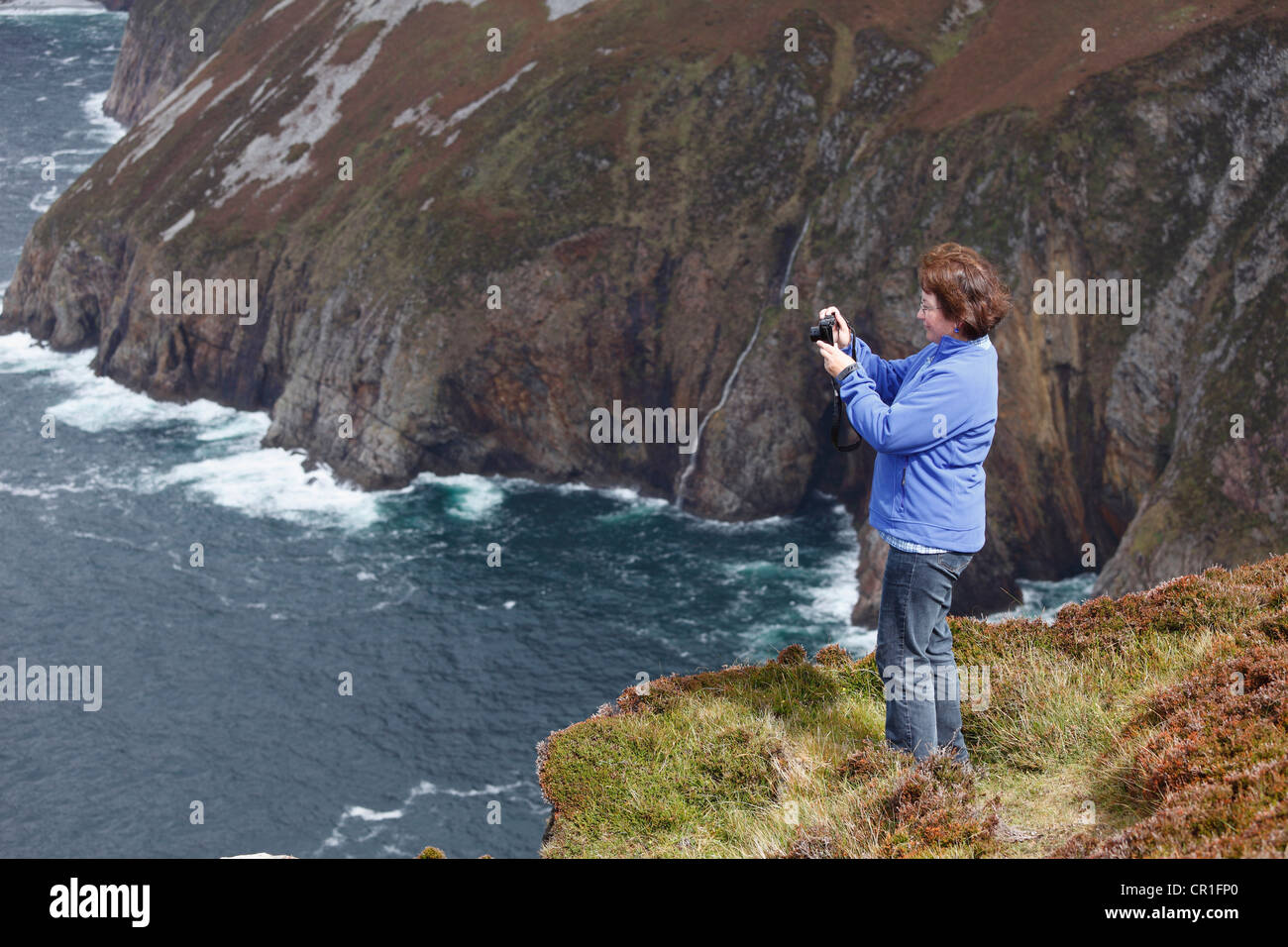 Mujer toma fotografías con una cámara digital compacta, en los acantilados de Slieve League, Condado de Donegal, Irlanda, Europa Foto de stock