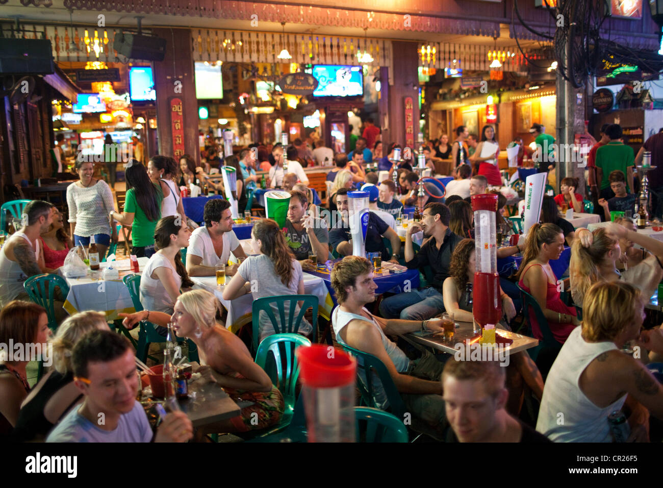 Mochileros y turistas extranjeros beber y comer en la noche en un bar al aire libre en la calle Khao San Road, Bangkok, Tailandia Foto de stock