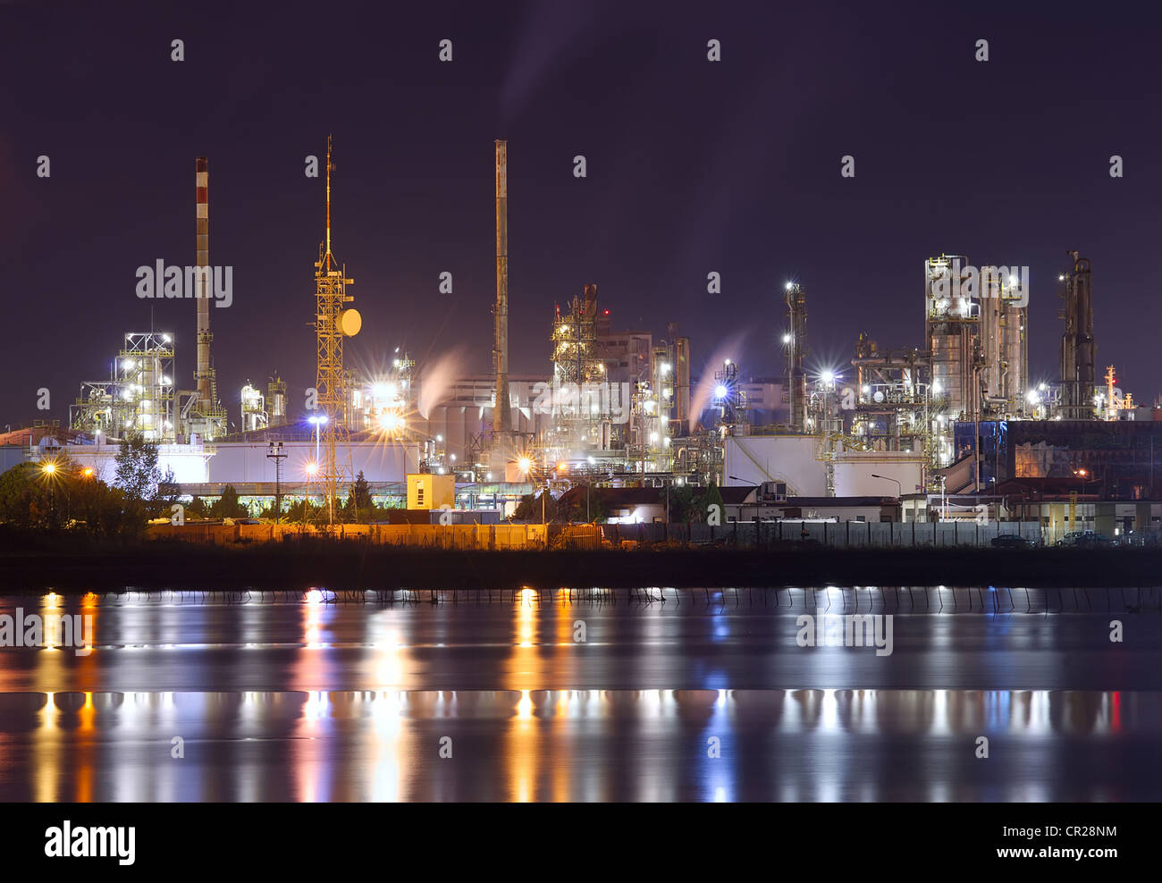 Escena nocturna de planta petroquímica con agua reflexión Foto de stock