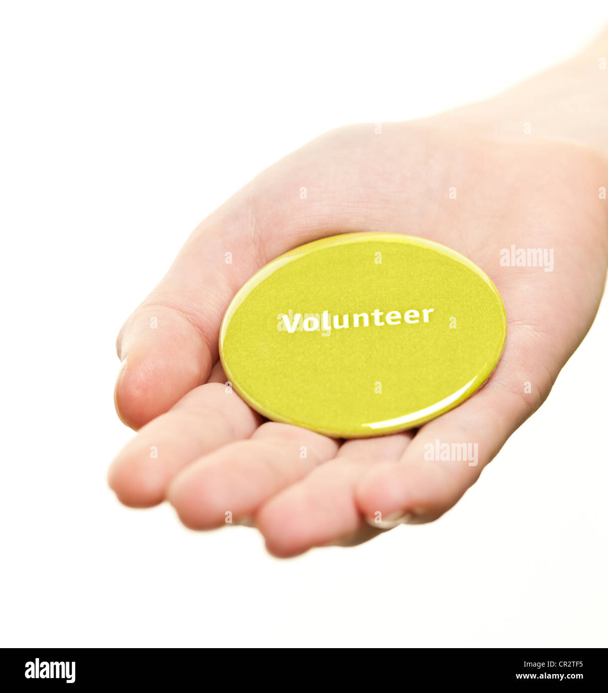 Mano sujetando el botón redondo verde voluntario aislado en blanco Foto de stock