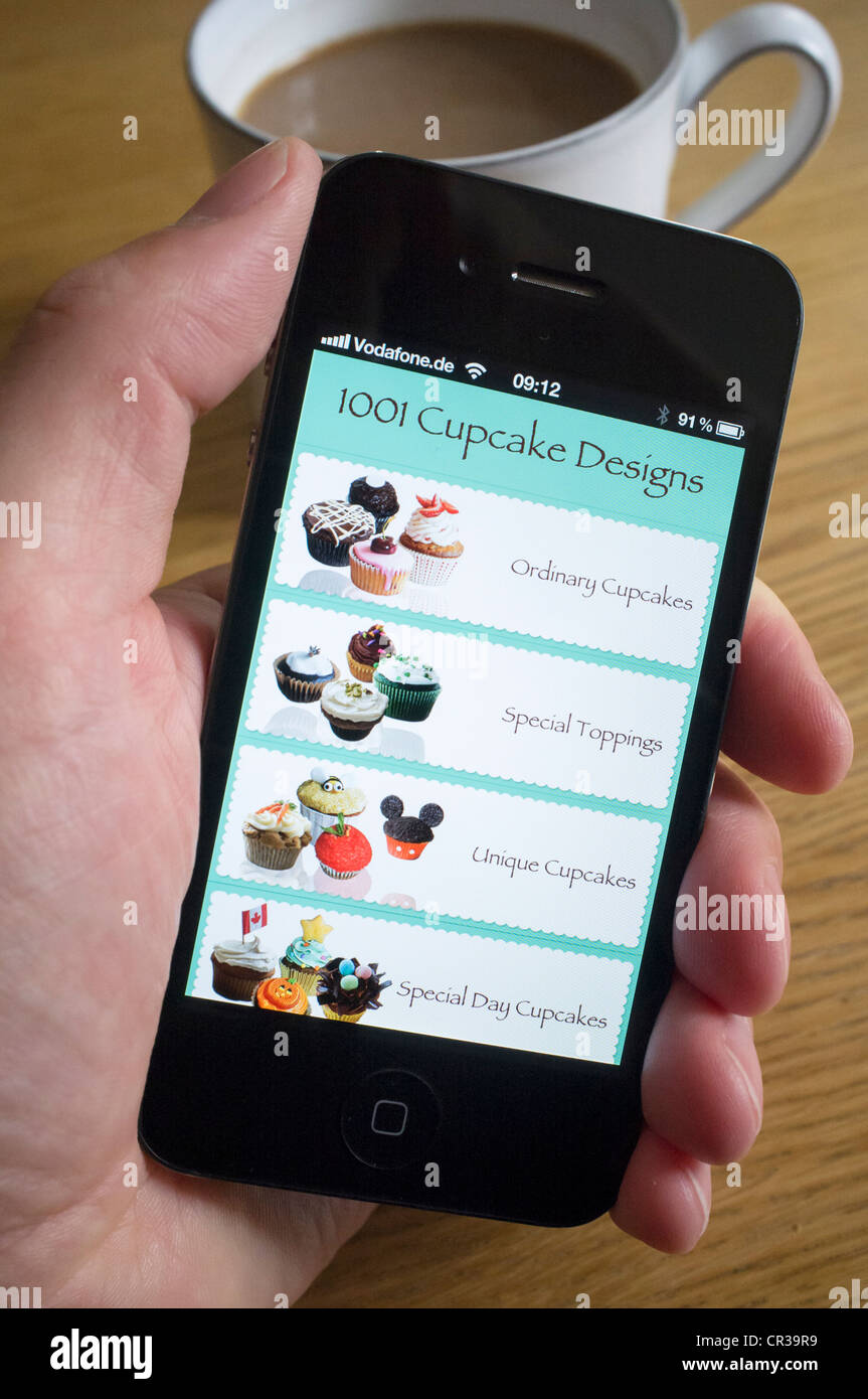 Utilizando un iPhone 4G teléfono inteligente para buscar recetas de pastelitos Foto de stock