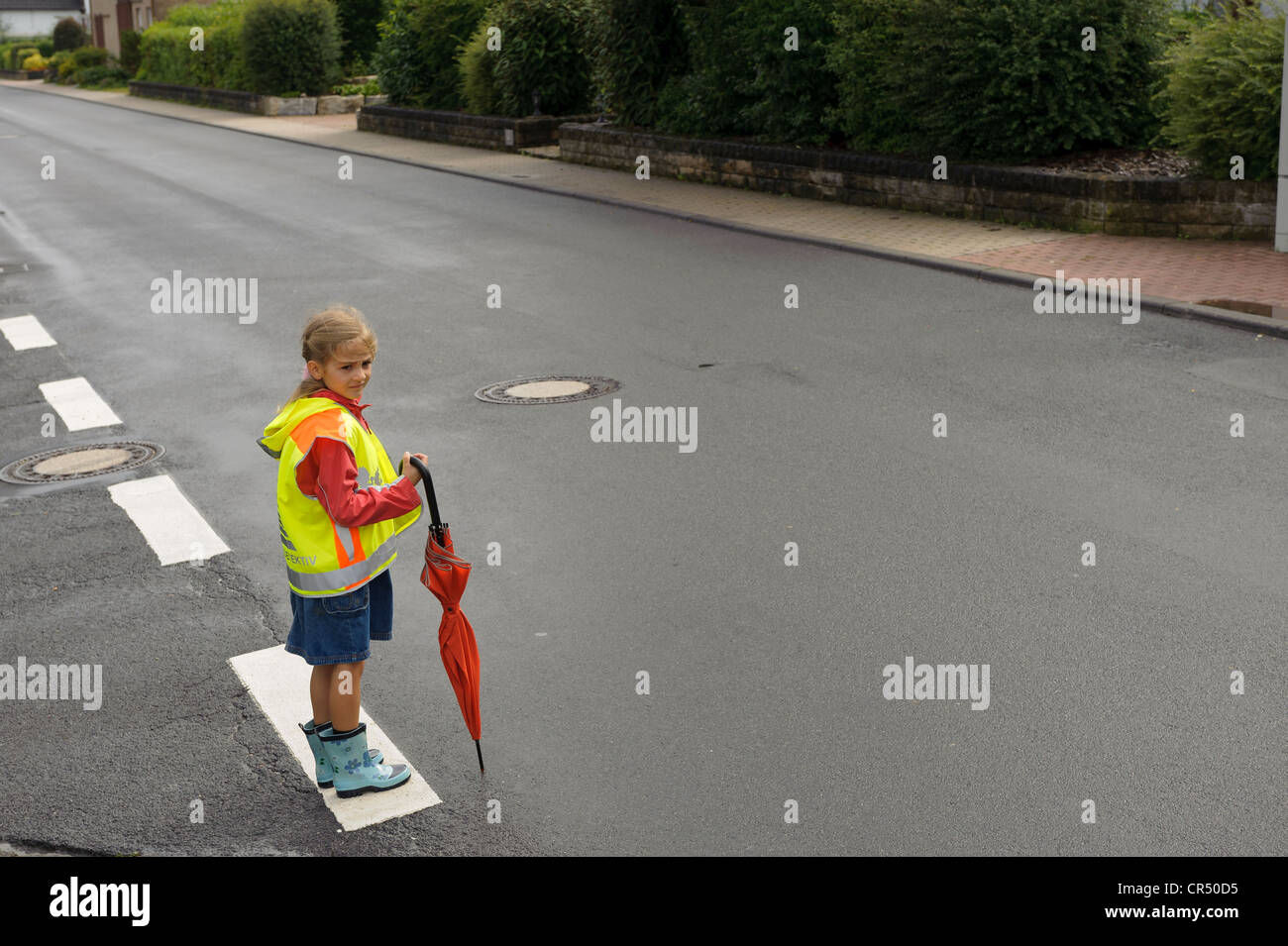 Niña de 7 años con chaleco amarillo para los niños de la escuela esperando  para cruzar la calle principal, Assamstadt húmeda, Baden-Wuerttemberg  Fotografía de stock - Alamy