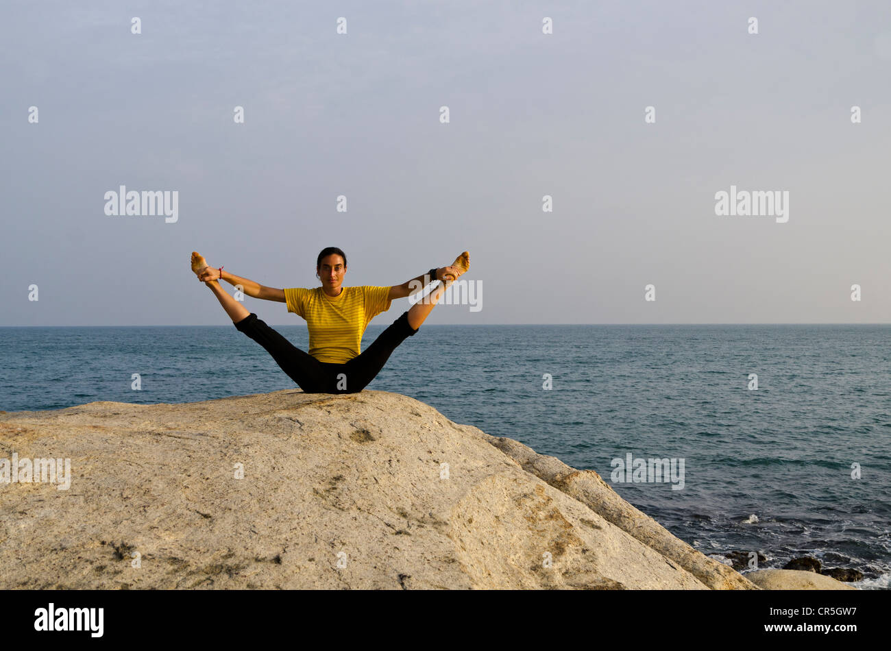 Una mujer en una posición de yoga, una variación de Paschimothanasana, por el mar en Kanyakumari, Tamil Nadu, India, Asia Foto de stock