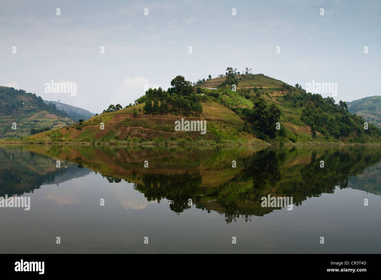 Hill se refleja en la superficie lisa del Lago Bunyonyi, en el oeste de Uganda, África Foto de stock