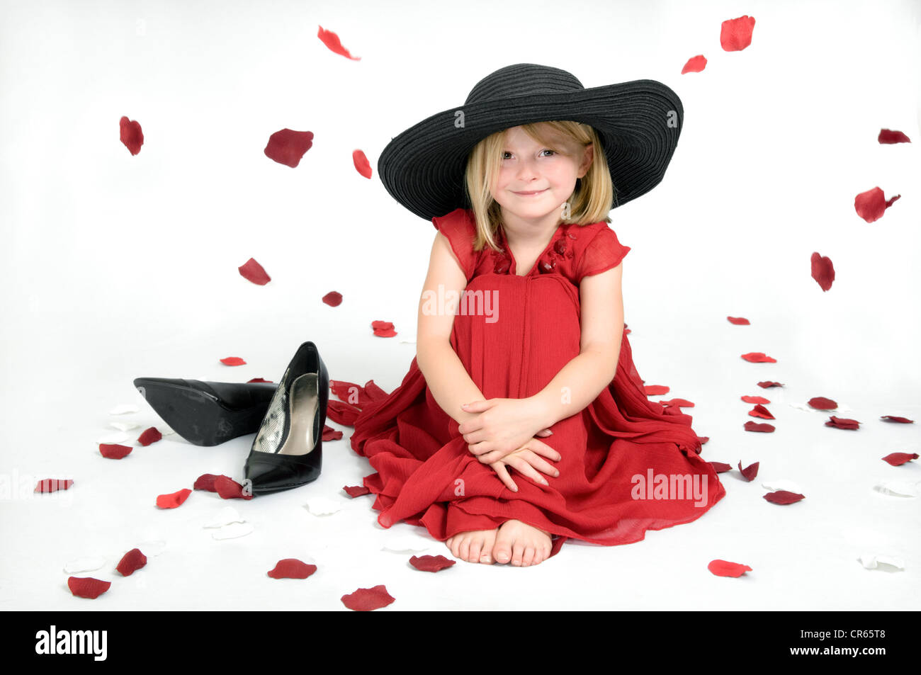 Studio imagen del Cáucaso en una niña de 7 años jugando a vestir vestido  rojo sobre un fondo blanco con pétalos de rosas Fotografía de stock - Alamy