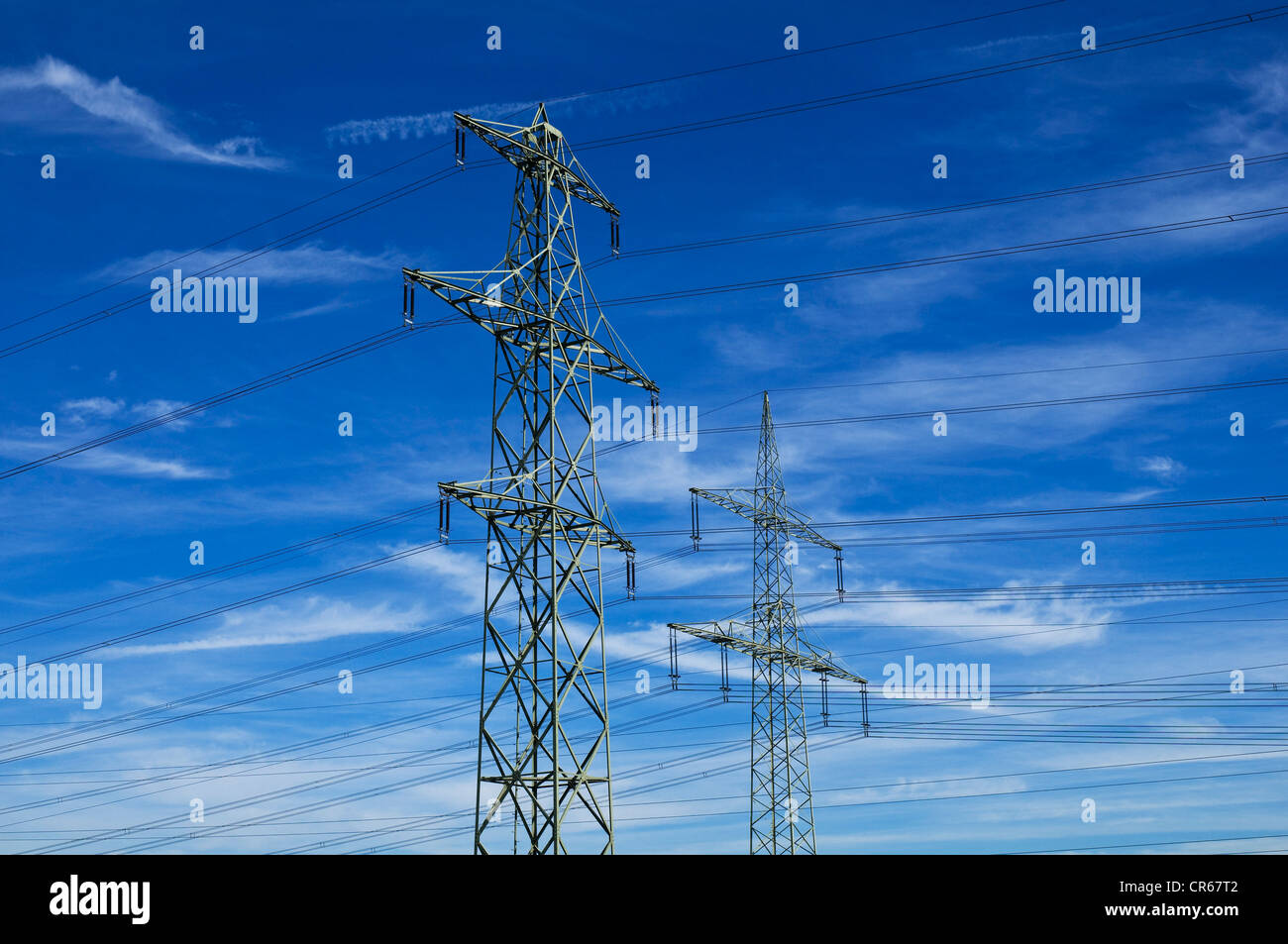 Dos torres eléctricas contra el cielo azul con nubes cirrostratus Foto de stock