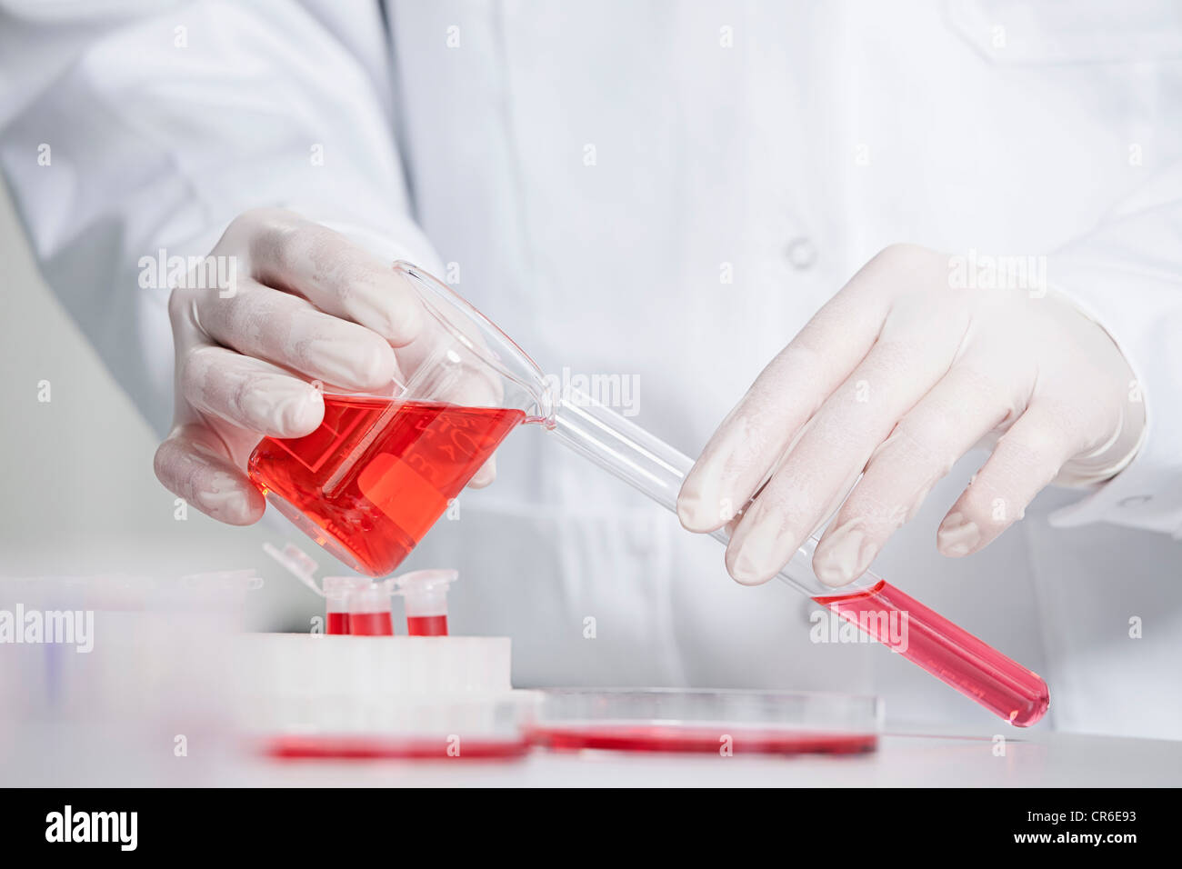 Alemania, Baviera, Munich, científico vertiendo líquido rojo en el tubo de ensayo en un laboratorio de investigación médica. Foto de stock