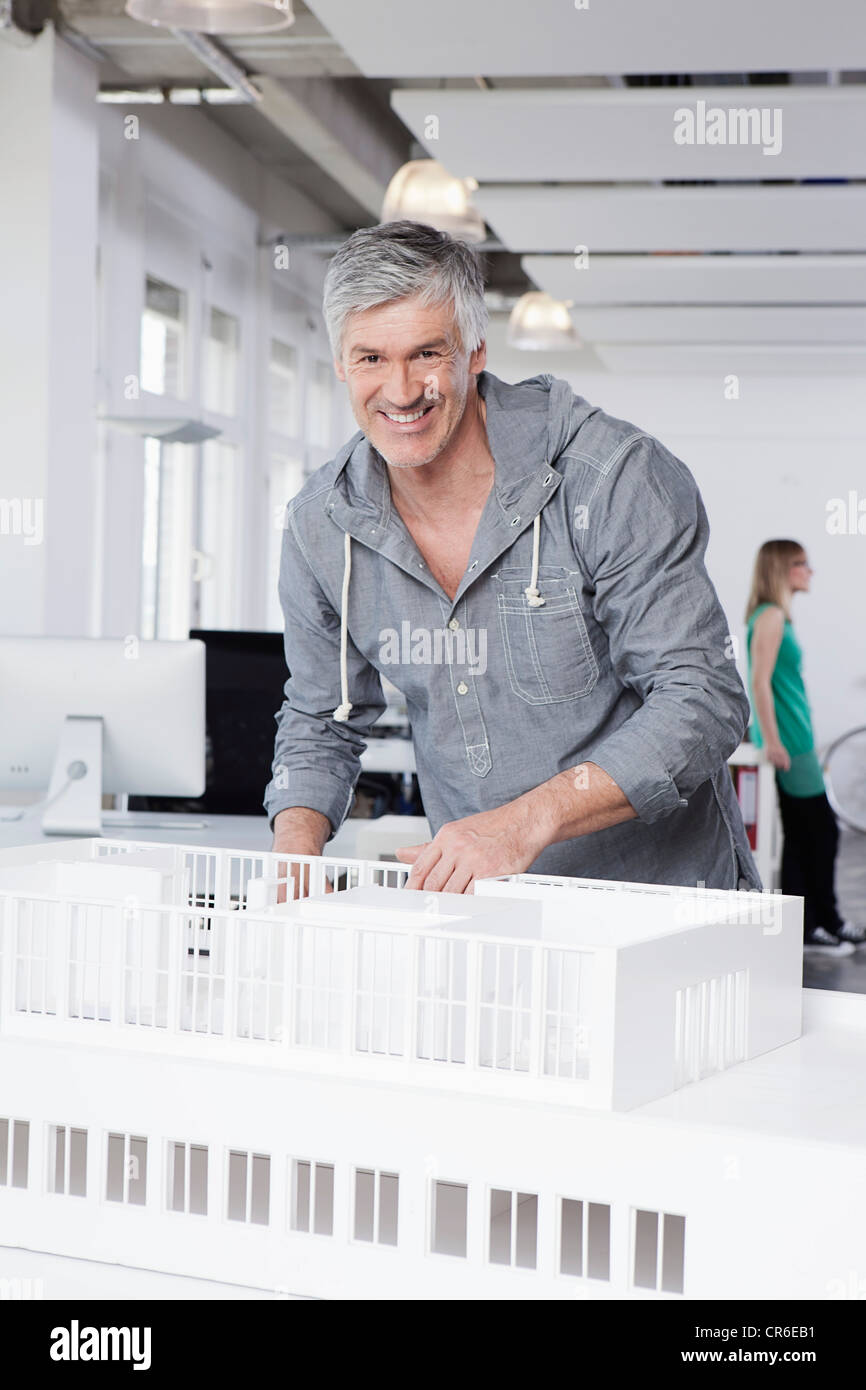 Alemania, Baviera, Munich, hombre de pie con el modelo arquitectónico en Office Foto de stock