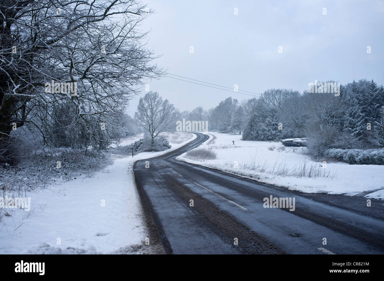 Carreteras heladas en Ranmore común en invierno. Cubiertas de nieve y bosques comunes Foto de stock