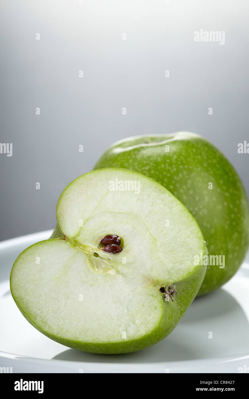 Dos Verde Manzana Granny Smith, una manzana entera y una manzana cortada por la mitad Foto de stock